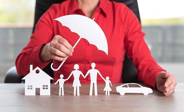 Asset protection attorney holding a paper cutout of an umbrella over a paper cutout family and estate